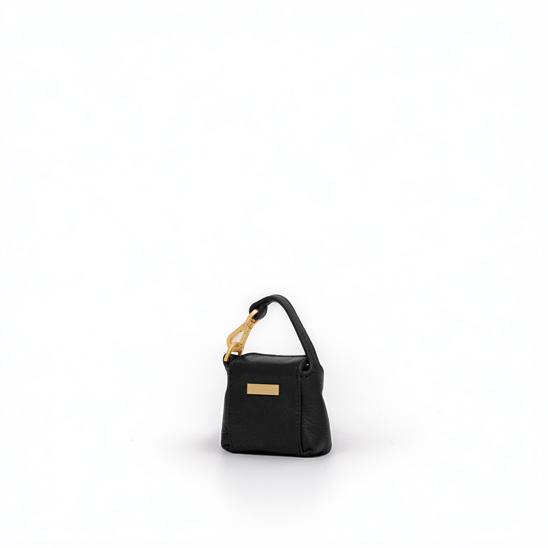 A small black leather handbag with a structured rectangular shape, a top handle, and gold-tone hardware, photographed on a clean white background.