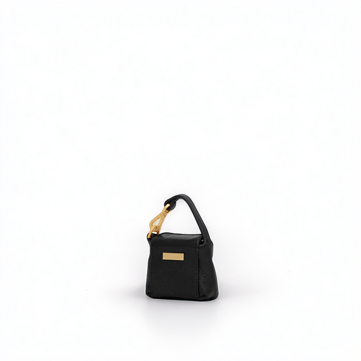 A small black leather handbag with a structured rectangular shape, a top handle, and gold-tone hardware, photographed on a clean white background.
