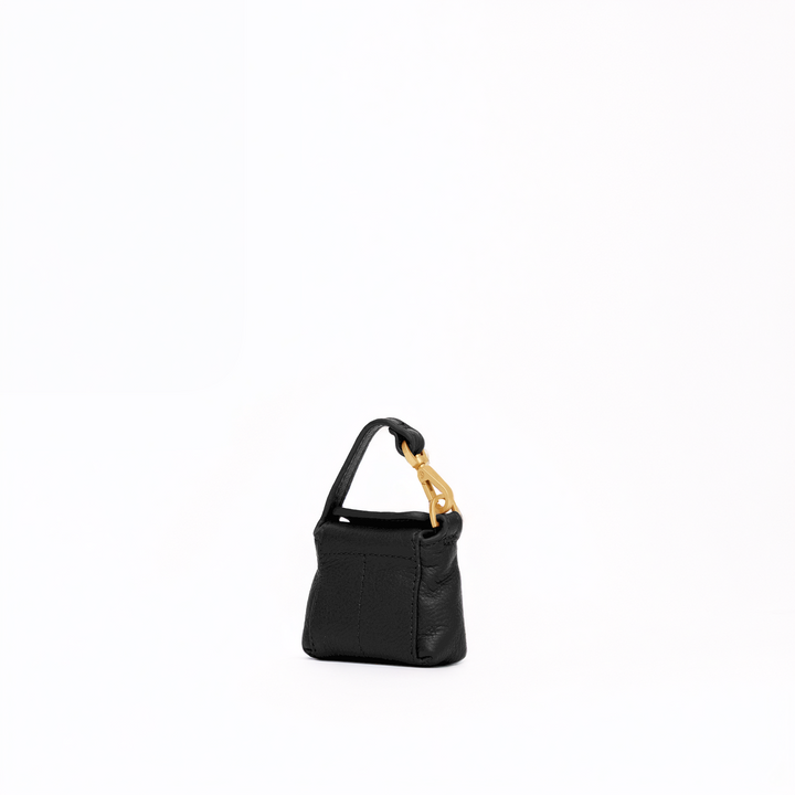 A miniature black textured leather handbag with a gold-tone lobster clasp and a short black strap, set against a solid white background.