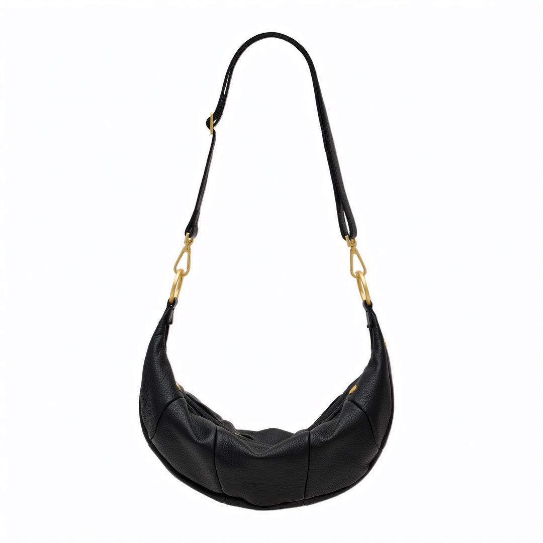 A black crescent-shaped leather shoulder bag with gold-tone hardware and a long adjustable strap, shown against a plain white background.