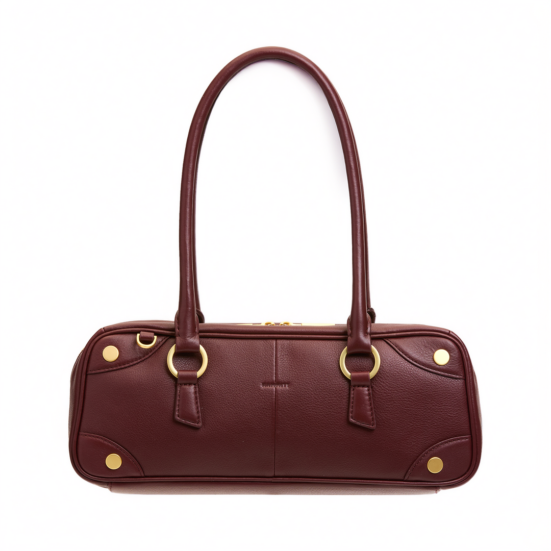 A burgundy pebbled leather handbag with gold-tone hardware, featuring dual top handles, a structured oval body, and decorative gold rivets on a plain white background.