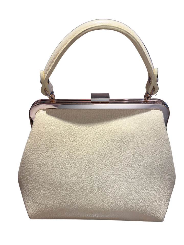 A cream-colored pebbled leather handbag with a top handle and a metal frame closure, shown against a busy, reflective tiled background.