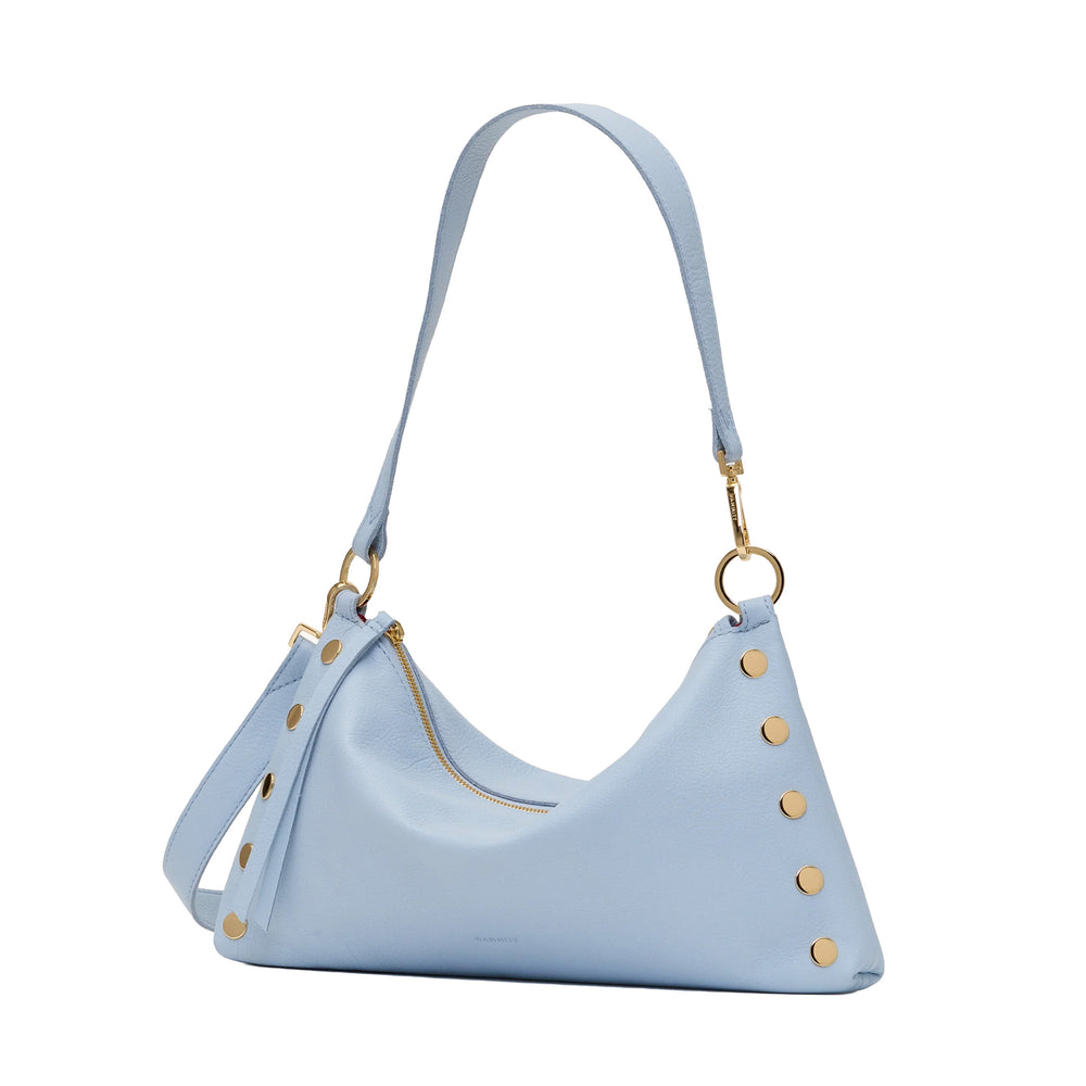 A light blue leather shoulder bag with gold-tone hardware, featuring a slouchy crescent shape, a zippered top, and decorative gold rivets along the side, shown on a plain white background.