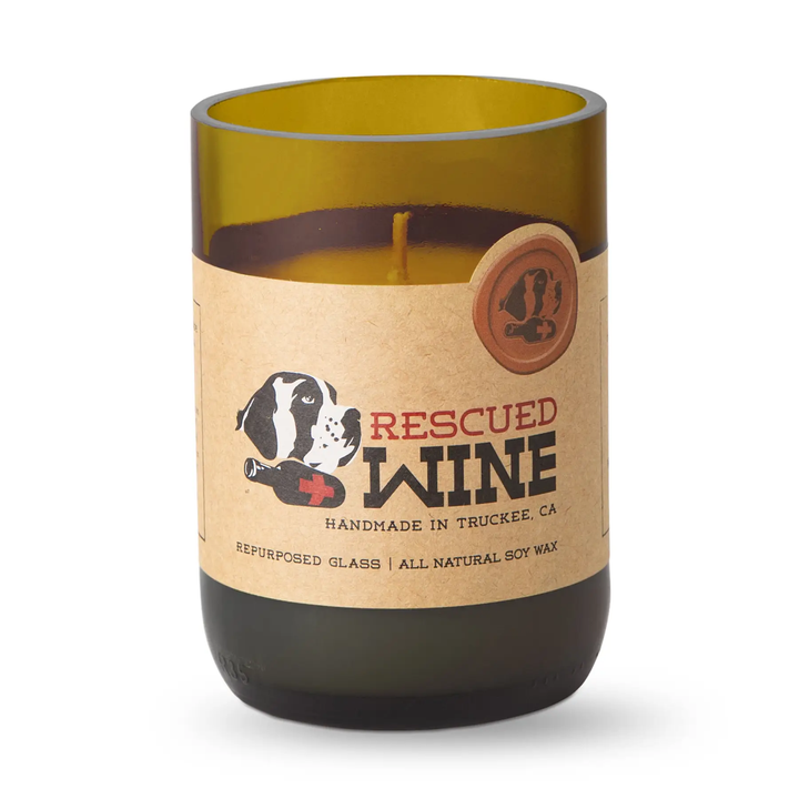 A candle in a repurposed olive-green glass bottle with a kraft paper label that reads &