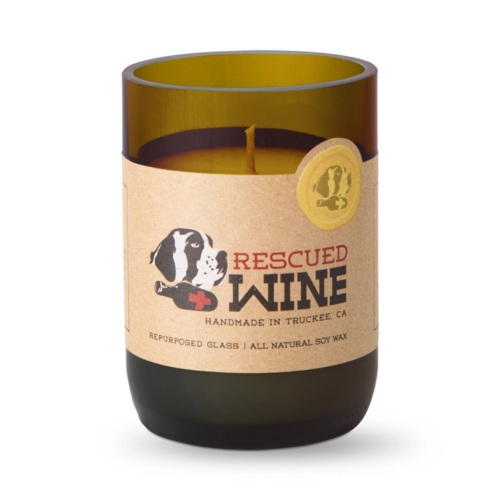 A candle in a repurposed amber glass wine bottle with a kraft paper label that reads &
