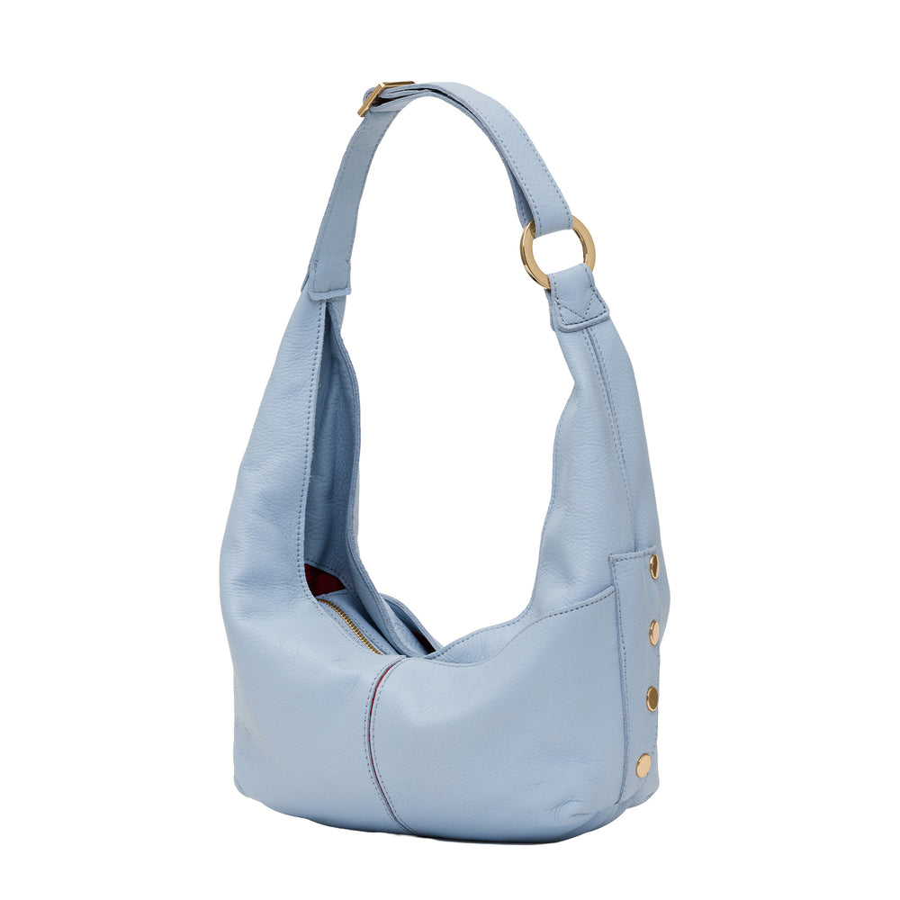 A light blue pebbled leather hobo shoulder bag with gold-tone hardware, including a ring on the strap and decorative studs on the side, shown against a plain white background.
