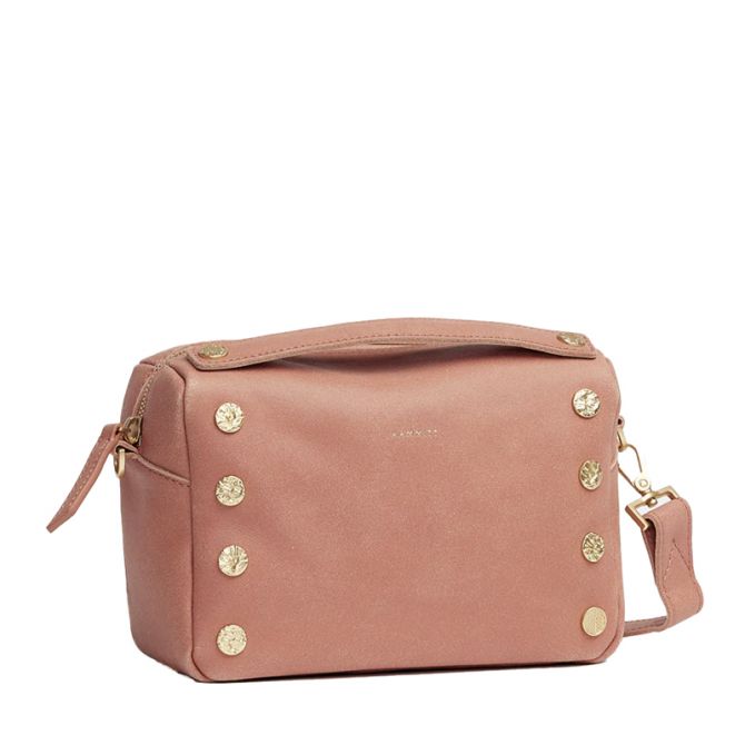 A dusty pink faux-leather crossbody bag with gold-tone hardware, featuring decorative round studs on the front, a top handle, and a detachable shoulder strap, shown against a plain white background.